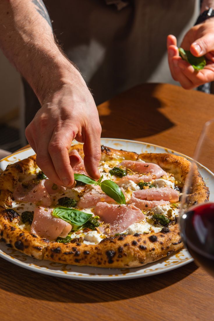 White pizza being finished with basil on a dining table.